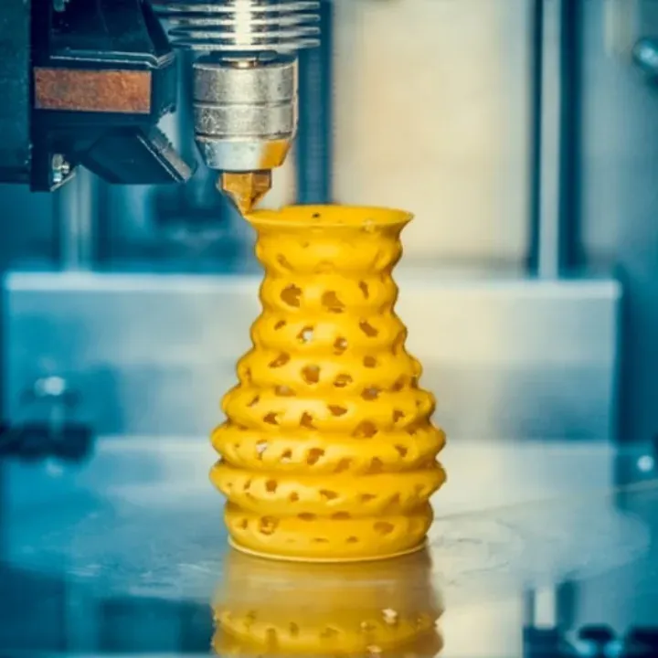 Pieza amarilla imprimiéndose en una impresora 3D